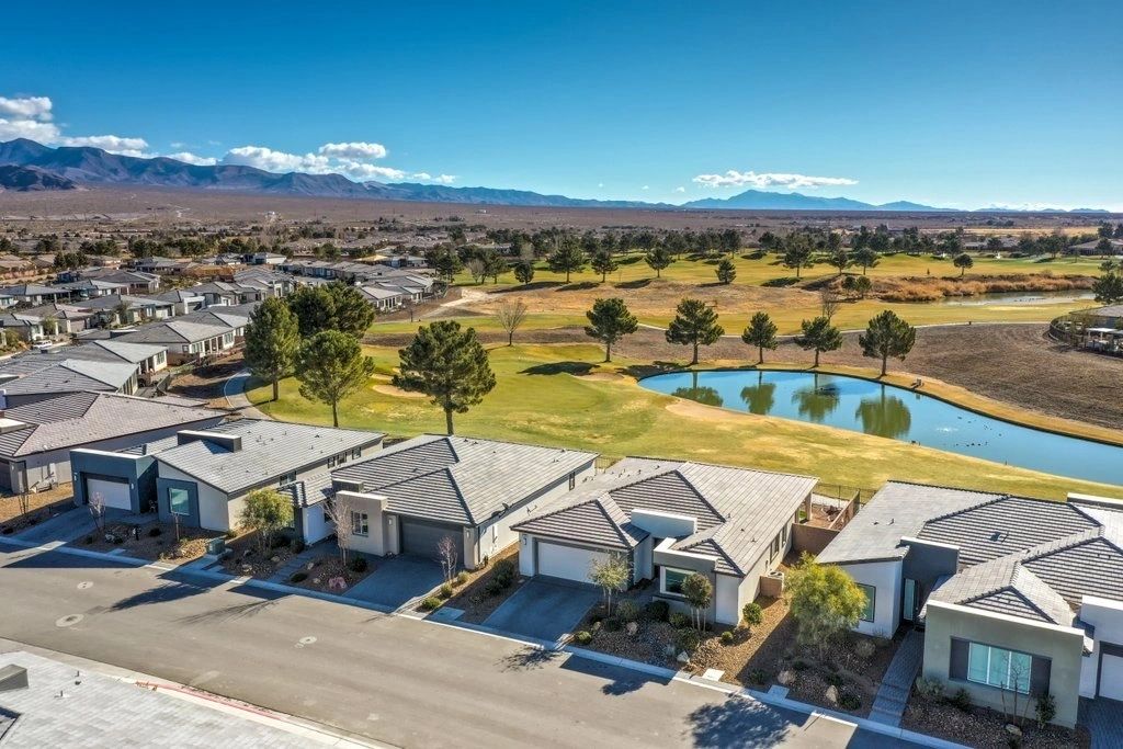 Aerial view of homes, a pond, and mountains