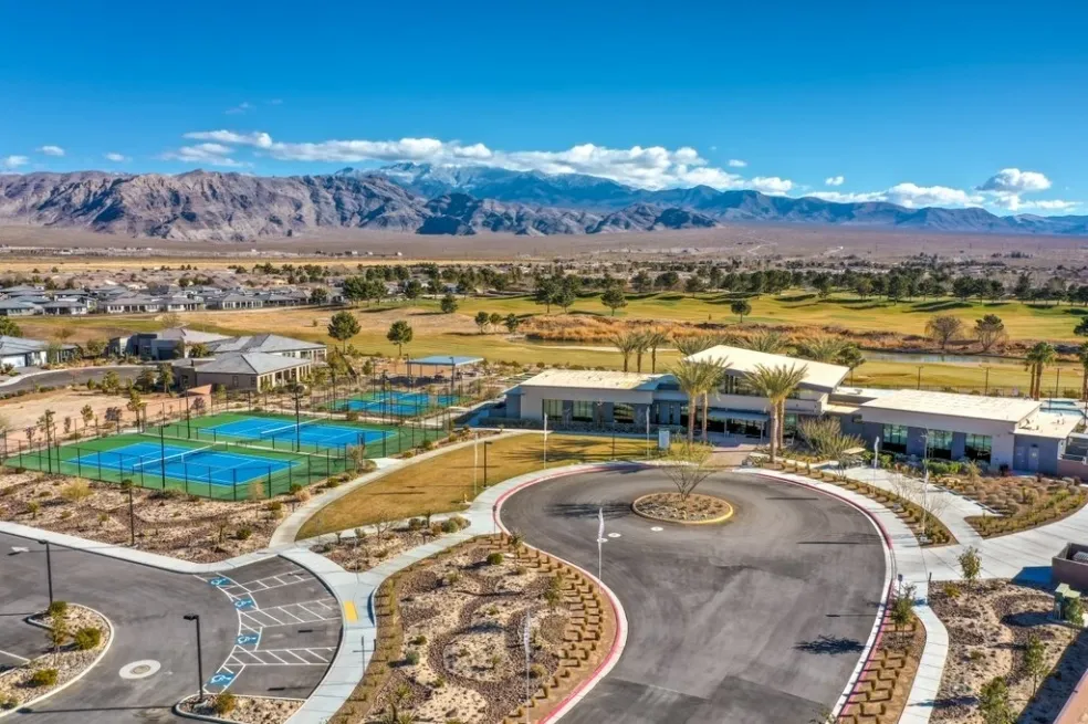 Aerial view of a community building, tennis courts, and mountains