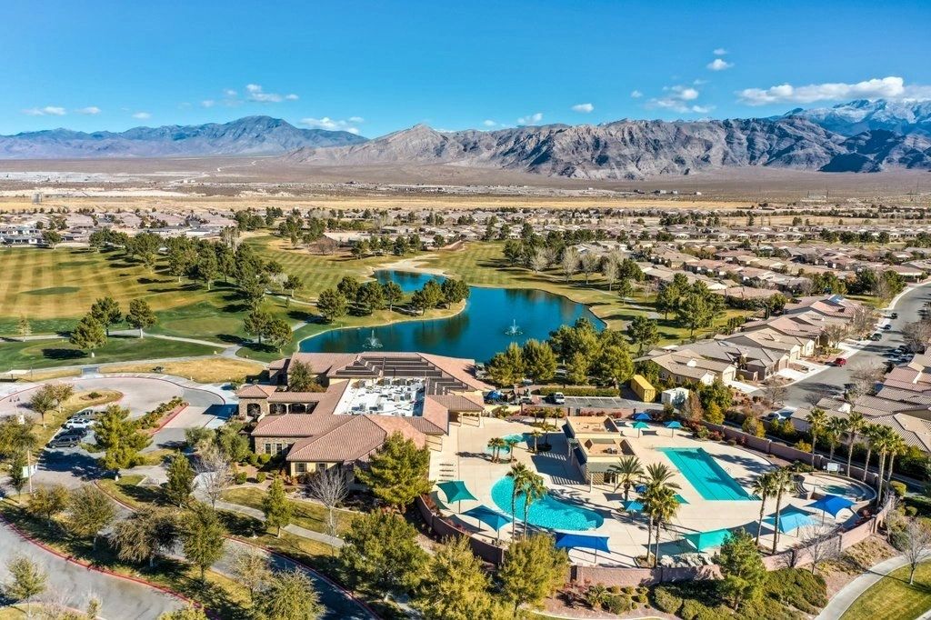Aerial view of a community pool and pond with mountains beyond