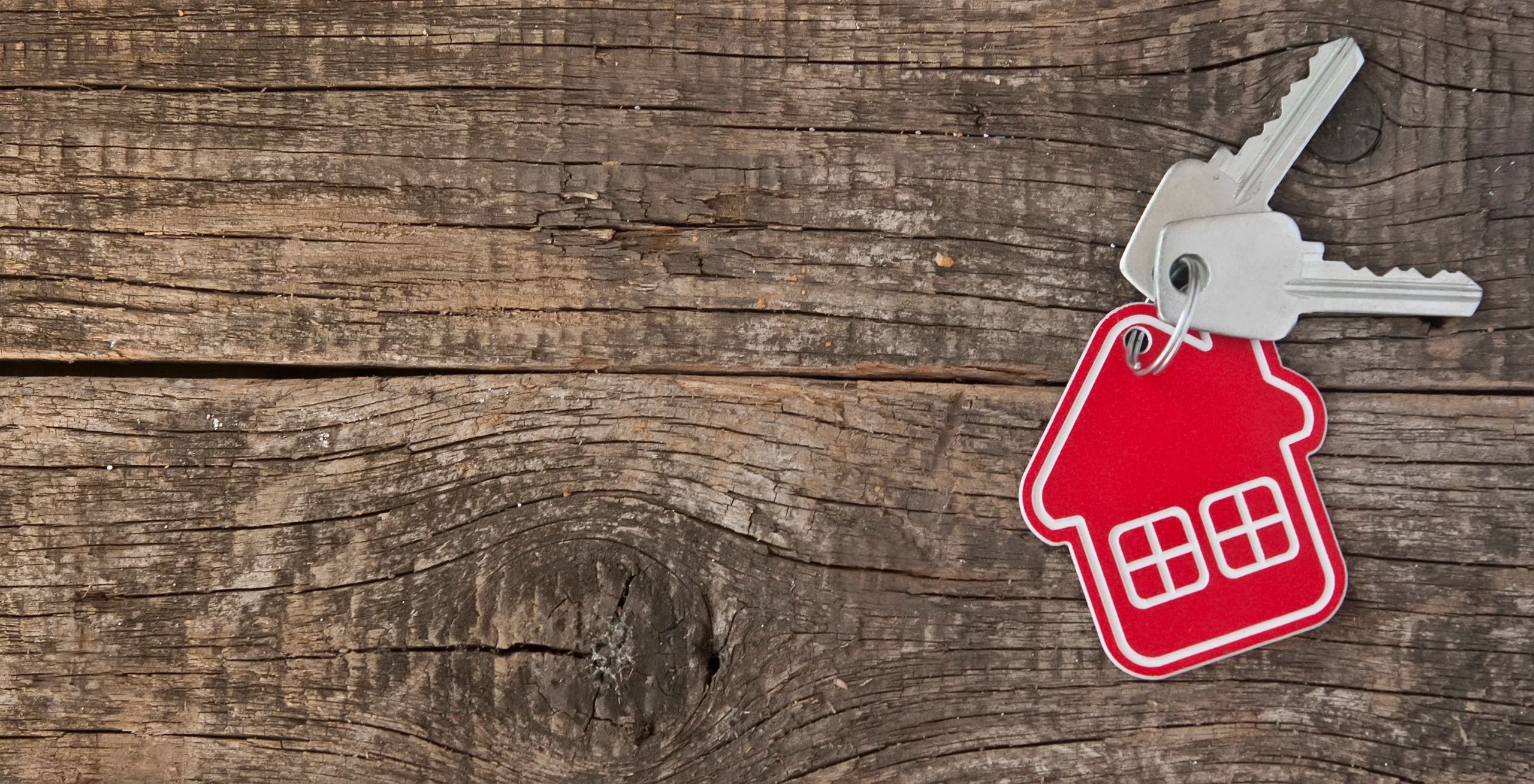 House keys held beside a home